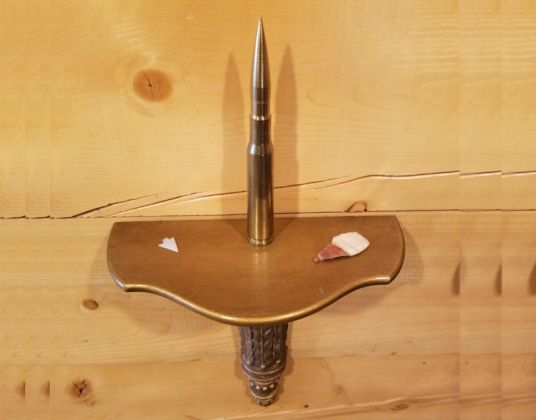 A wooden shelf with shells and a bullet shell.