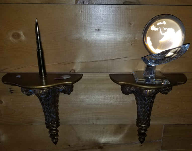 A pair of wall mounted shelves with one holding a pen and another holding a mirror.